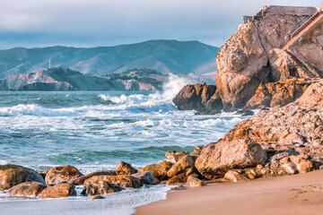 Wave splashes close-up. Crystal clear sea water hitting rock formations in the ocean in San Francisco Bay, blue water, pastel colors.