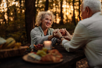 Grandmother holding hands with spouse while having a picnic