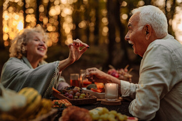 Elderly married couple eating grapes at picnic