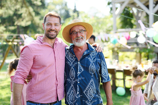 Mature son with his elderly father at a summer garden party outdoors. Concept of Father's Day and paternal love at any age.