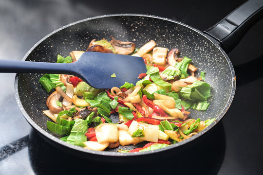 Stir-fried vegetables steaming in a frying pan, healthy vegetarian cooking with ingredients like bell pepper, mushroom, onions and pak choi or Chinese cabbage, selected focus