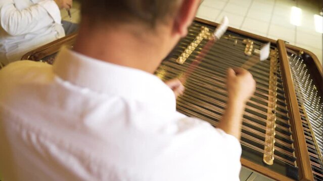 young Roma Gypsy male playing high energy fast paced song music rhythm on antique table cimbalom thin sticks with cotton tips complicated instrument ancient historic classical  baroque style indoor