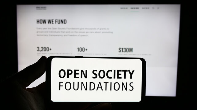 Stuttgart, Germany - 10-09-2023: Person holding smartphone with logo of organization Open Society Foundations (OSF) in front of website. Focus on phone display.