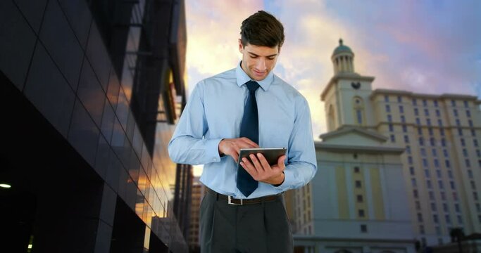 Composite view of biracial businessman using digital tablet against tall buildings and sunset sky