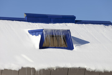 Snow-covered roof with icicles in nice winter day