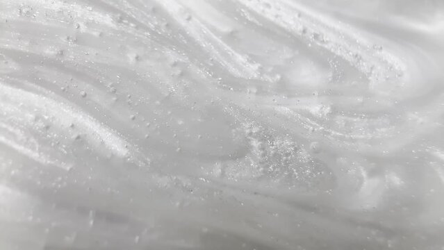 Abstraction of the light gray viscous fluid, having a heterogeneous structure with blotches and particles on its surface. Abstract CGI motion design on a light background