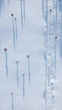 Top view of skiers and snowboarders skiing on a snow slope with a ski lift at the ski resort on a sunny day.