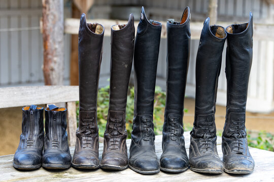 schmutzige alte Reitstiefel Leder bereit zur Reinigung aufgereiht auf einem alten Holztisch