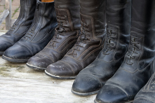 schmutzige alte Reitstiefel Leder bereit zur Reinigung aufgereiht auf einem alten Holztisch