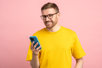 Pleasant smiling man in glasses with leer sly cunning look holding smartphone after receiving good...
