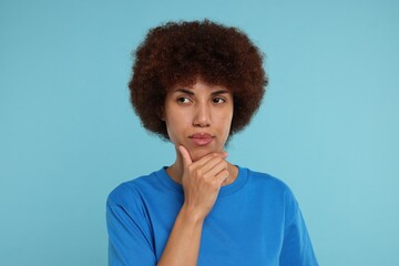 Portrait of thoughtful young woman on light blue background