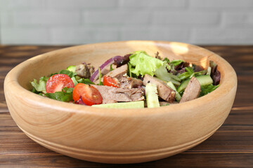 Delicious salad with beef tongue and vegetables on wooden table, closeup