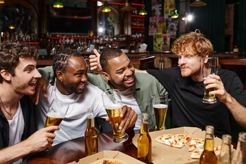group of happy multiethnic friends chatting and holding glasses of beer, spending time in bar