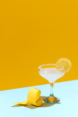 Sweet and sour, popular margarita cocktail with lemon slice decoration isolated over yellow background. Concept of alcohol drinks, party, holidays, bar, mix. Poster. Copy space for ad