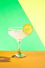 Poster. Zesty margarita adorned with salt and lemon slice showcased against dynamic vibrant contemporary colored studio background.