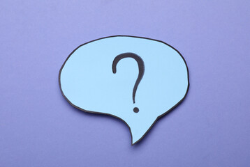Paper speech bubble with question mark on violet background, top view