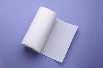 Roll of tissue towels on violet background, top view