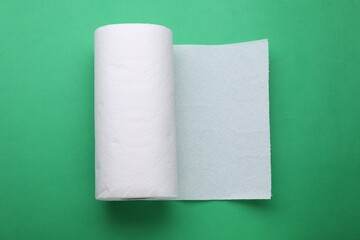 Roll of tissue towels on green background, top view