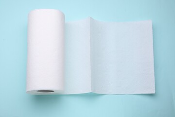 Roll of tissue towels on light blue background, top view