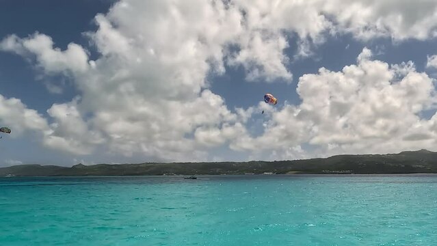 Clear blue sky and two paragliders hovering above the sea