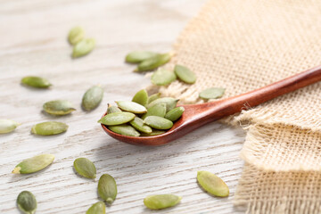 Spoon with peeled seeds on light wooden table