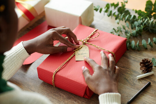 Hands of woman adjusting Merry Christmas tag on wrapped present