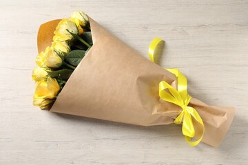 Beautiful bouquet of yellow roses with ribbon on wooden table, top view - Powered by Adobe