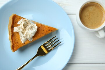 Delicious pumpkin pie with whipped cream, fork and cup of coffee on white wooden table, flat lay