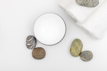 Flat lay, top view Spa aromatic sea salts with Spa stones on white background. Spa cosmetics , cream , flower