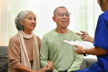 Smiling senior couple listening attentively to nurse or general practitioner explaining therapy...