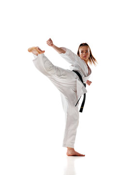 Young woman in white uniform training martial arts in action isolated over white studio background.