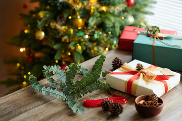 Fototapeta na wymiar Eucalyptus branches and pine cones on table next to wrapped Christmas presents