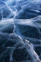 Abstract winter natural ice background of blue icy surface with cracks of frozen Baikal Lake in...