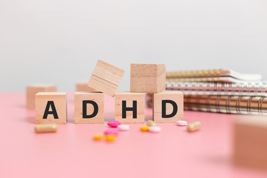 wood cube block Abbreviation of ADHD with Stethoscope and pills on pink table. Attention Deficit Hyperactivity Disorder. ADHD concept. - Powered by Adobe
