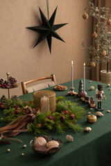 Close up of christmas table with candle with candlestick, wreath, nuts, sculptures, personal...