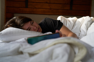 Woman in bed checking social media with smartphone