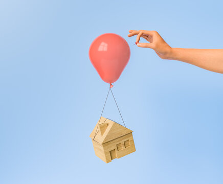 hand blowing up a balloon with a tied house