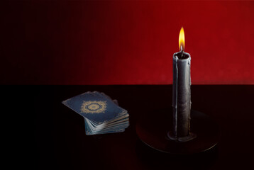 Black candle and tarot cards on dark background with space for text. Tarot cards and esoteric...
