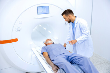 Experienced radiologist encouraging senior patient before MRI or CT scanning procedure in hospital.