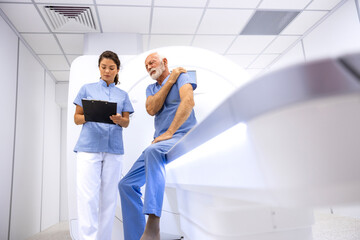 Senior patient complaining about pain in shoulders before going to MRI or CT scanning procedure in...