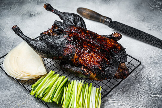 Whole roast Peking duck with herbs, sauce, rice Pancake, Cucumber and onion. White background. Top view