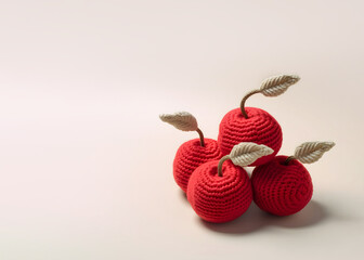 Knitted cherries, creative minimalistic fruit composition with copy space, pastel background.