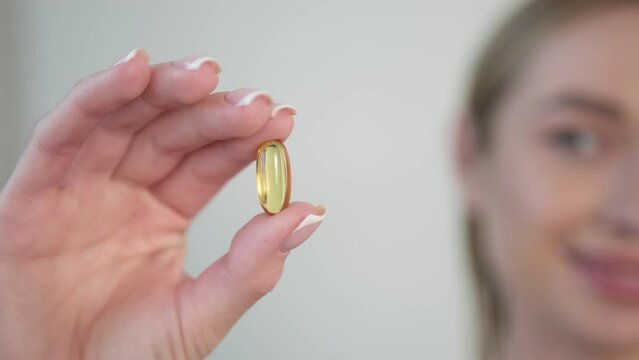 The girl's hand holds an omega tablet close-up.