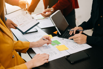  UX developer and ui designer brainstorming about mobile app interface wireframe design with customer breif and color code at modern office.