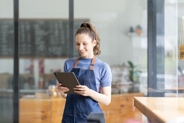 Startup successful small business owner sme beauty girl stand with tablet smartphone in coffee shop restaurant. Portrait of asian tan woman barista cafe owner. SME entrepreneur seller business concept