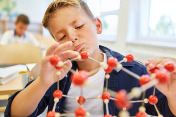 Curious schoolkid examining molecular structure in class