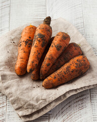 Dirty carrots on a white wooden background. Vegetables, harvesting.