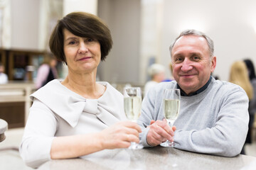 Mature man and woman drinking champagne in theater lobby