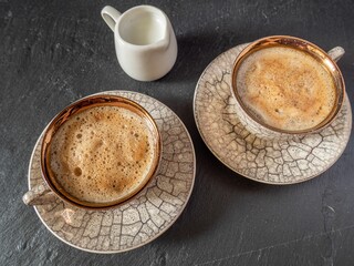 Set of two cups of cappuccinos on a light gray, table