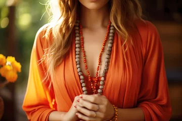 Tuinposter Young woman, yoga teacher holding a mala beads yoga necklace © Jasmina